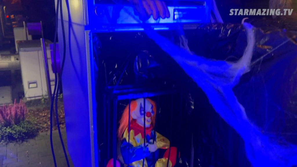 Vorgarten Halloween Rheydt: Gruseliger Paketkasten mit Hand im Briefschlitz und Clown im Käfig Unheimlicher Paketkasten beim Vorgarten Halloween Rheydt mit greifender Hand im Briefschlitz und Clown, der aus dem Käfig auszubrechen versucht und die Gitter verbiegt.